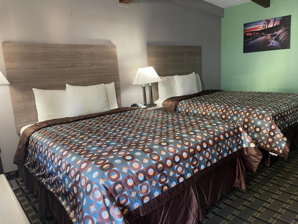 A hotel room with two twin beds, wooden headboards, and a geometric-patterned bedspread.