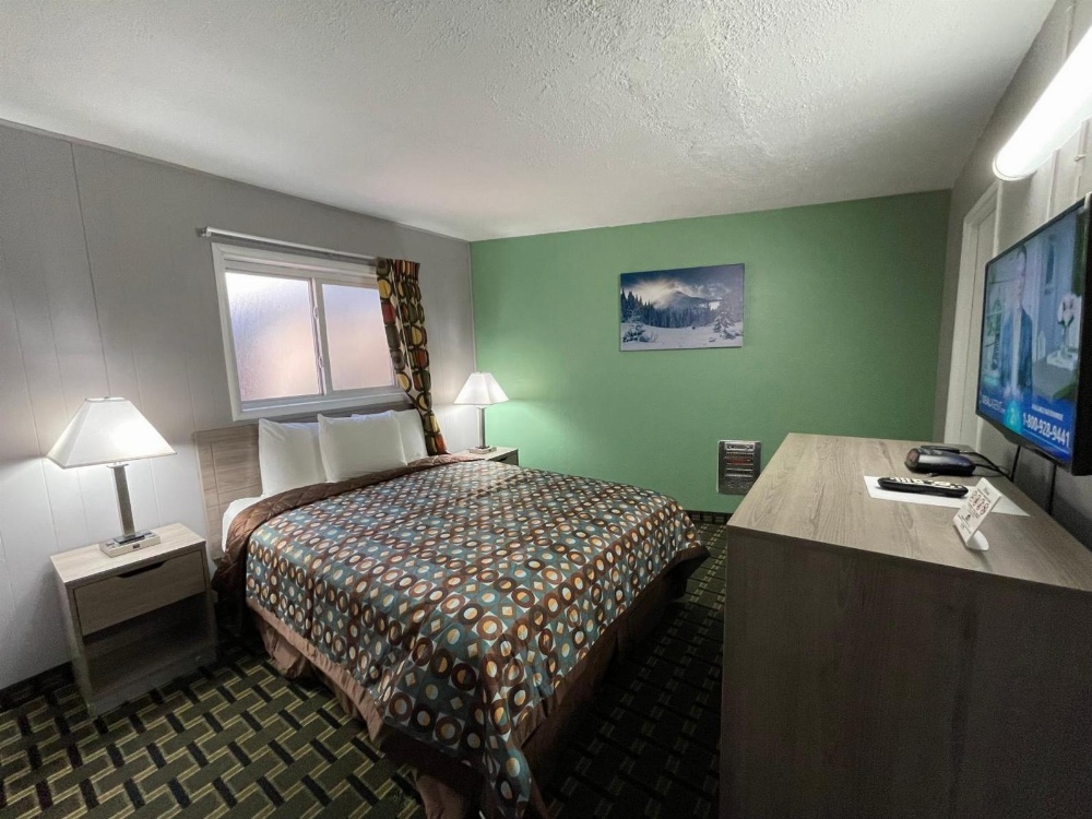 A standard hotel room with a bed, nightstands, a TV, and a window.