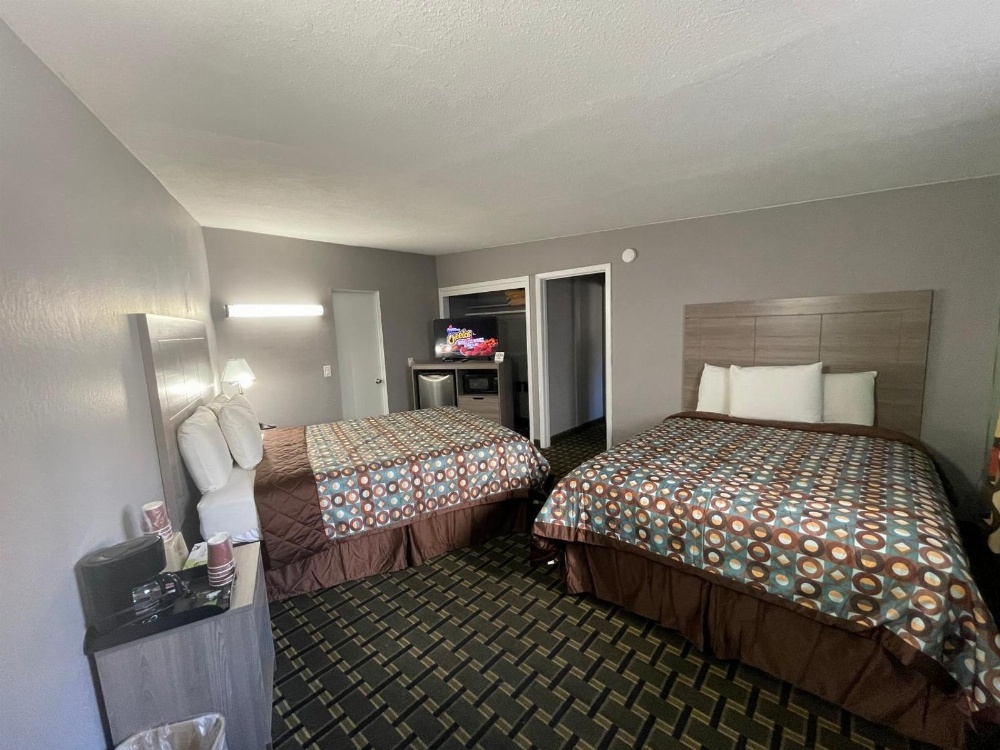 A hotel room with two beds, a nightstand, and a coffee maker.