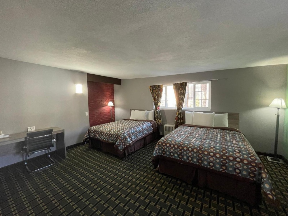 A hotel room with two beds, a desk, and a window.